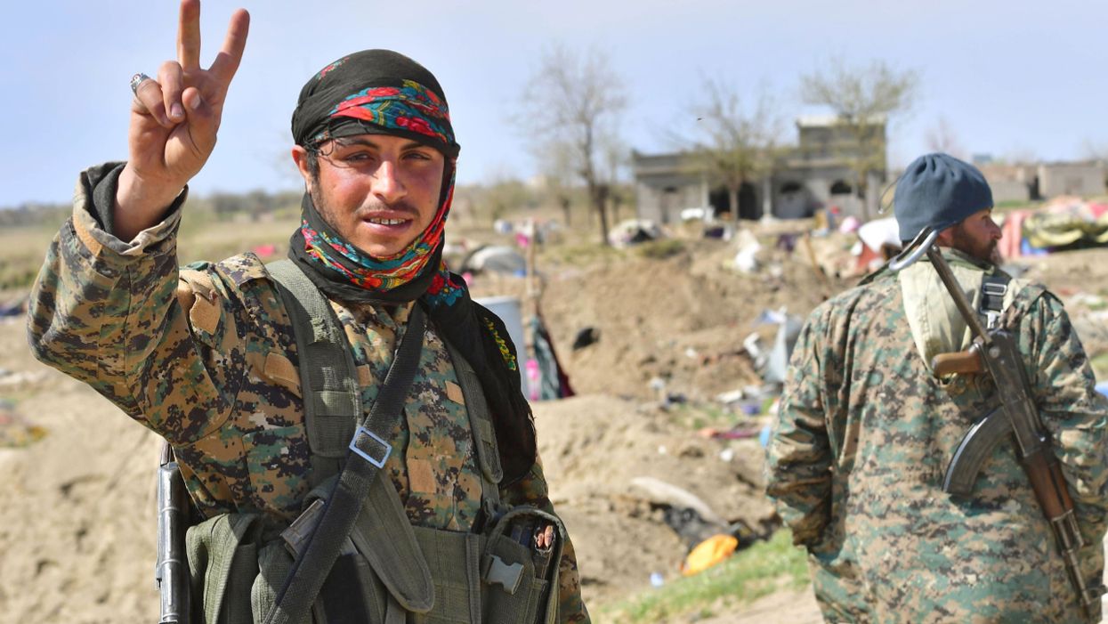 A picture taken on March 23, 2019 shows a fighter of the US-backed Kurdish-led Syrian Democratic Forces (SDF) flashing the V for victory sign in the fallen Islamic State group's last bastion in the eastern Syrian village of Baghuz after defeating the jihadist group.