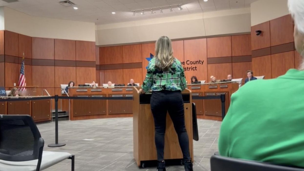 Angry parent reads sexually charged passage from HS library book to school board. Board member cuts her off, says children could be listening.