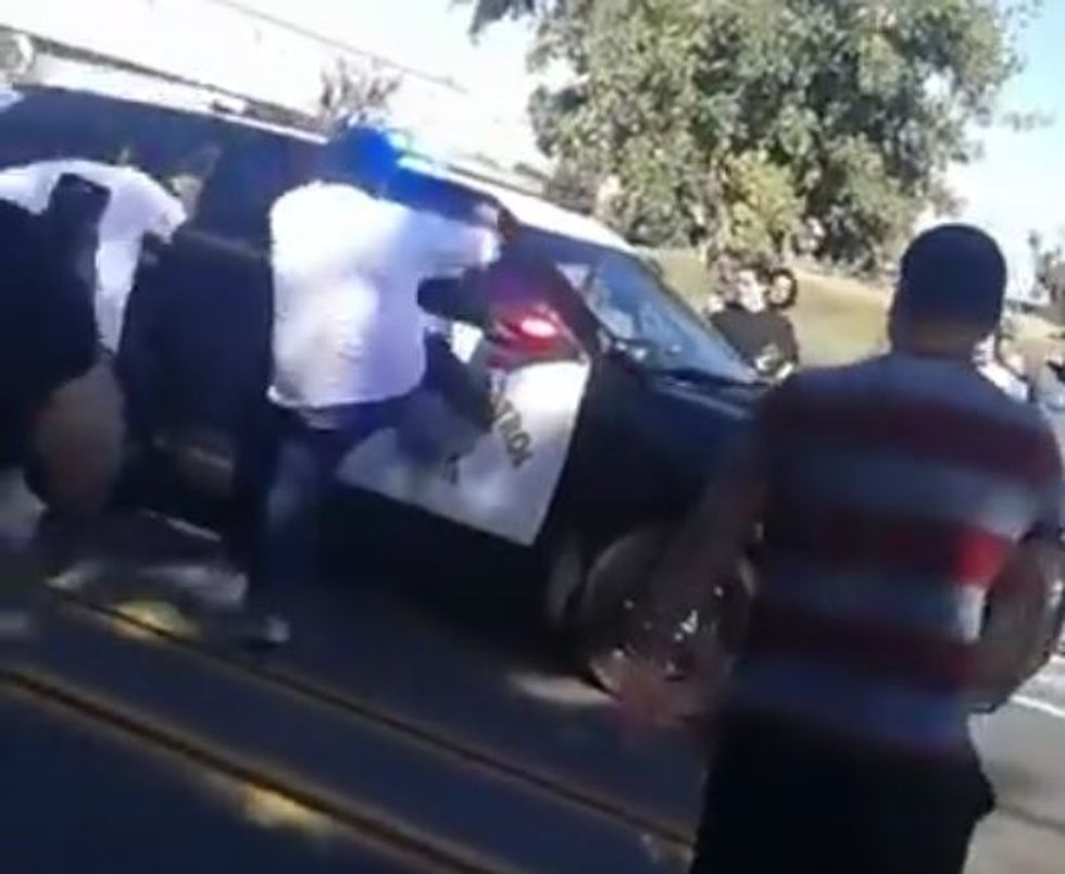 Rowdy crowd blocks street to cheer drivers pulling donuts. Watch what they do to cop who shows up.