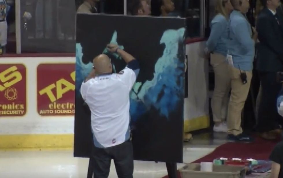 He sings 'The Star-Spangled Banner' while painting an image. Crowd goes nuts when finished product is revealed.