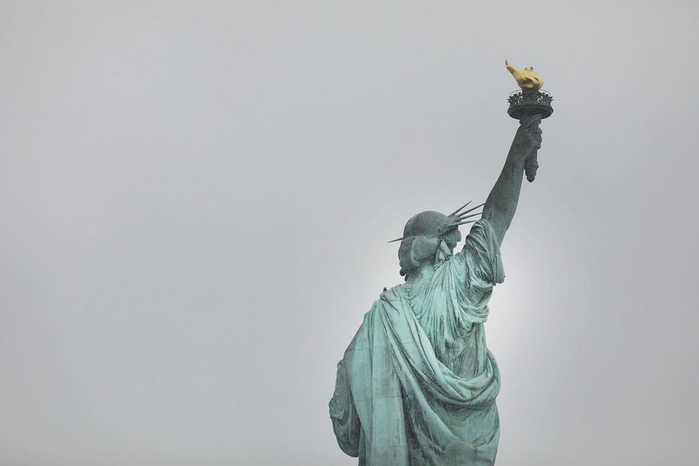 Activists unfurl "refugees welcome" banner on Statue of Liberty