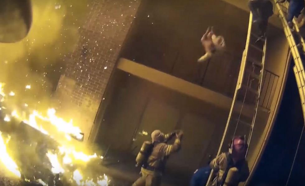 Watch: Amid raging apartment fire, child tossed from three stories up — and into firefighter's arms