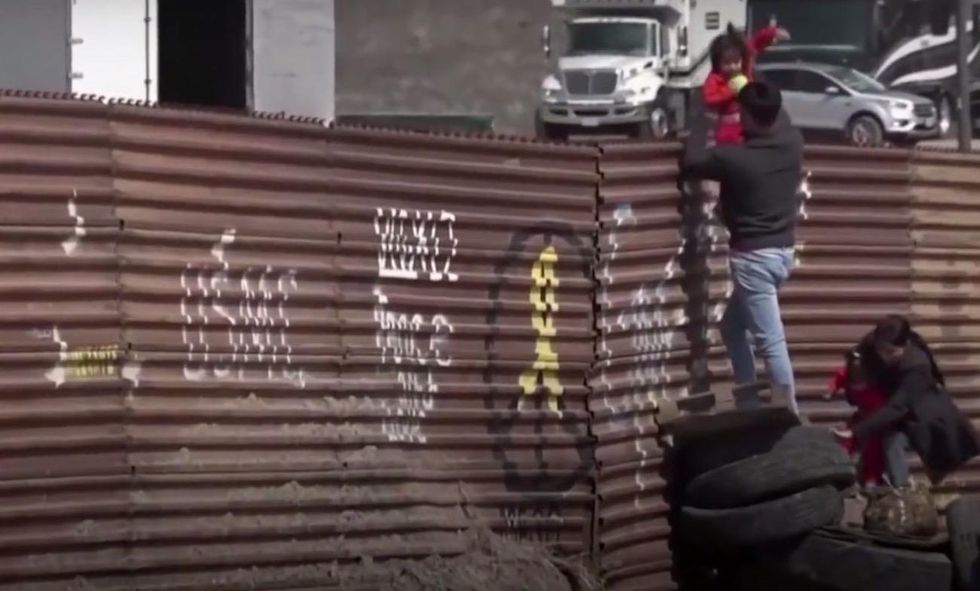 Toddlers passed over border fence into US as camera rolls — and apparently by Trump wall prototypes