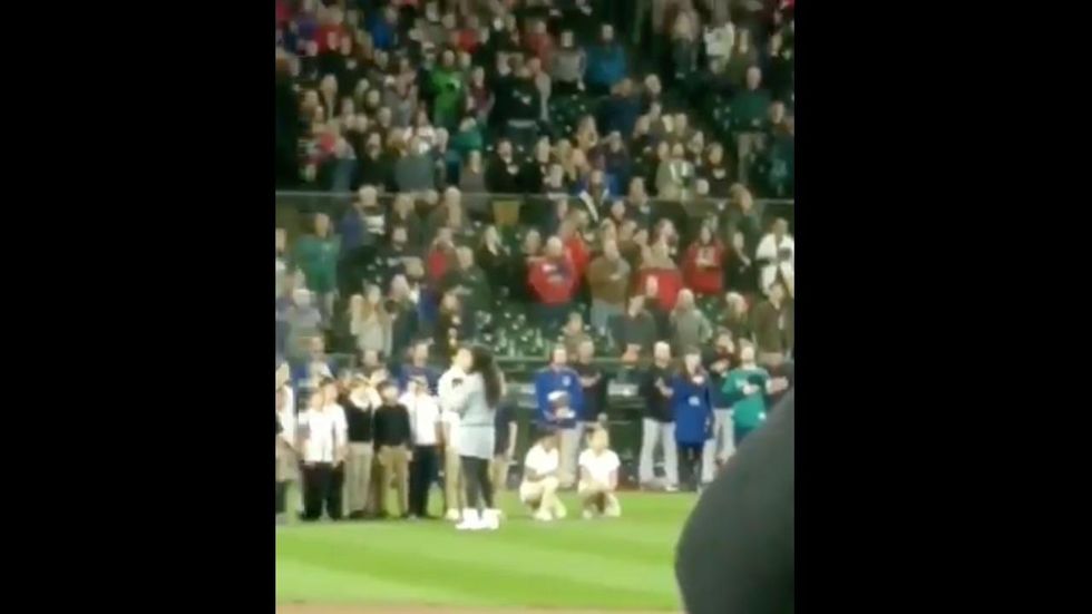 Elementary choir members take a knee during their performance of the national anthem before MLB game