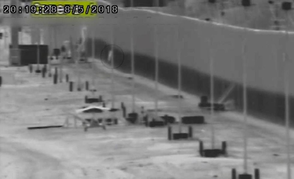 Security camera footage shows moment illegal immigrant falls from top of 30-foot border fence