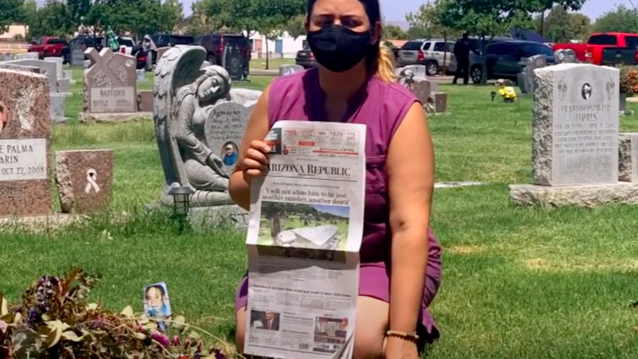 Masked woman kneeling on grave