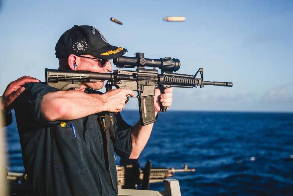 Navy torpedoes embarrassing post showing commanding officer firing rifle with backward and covered scope