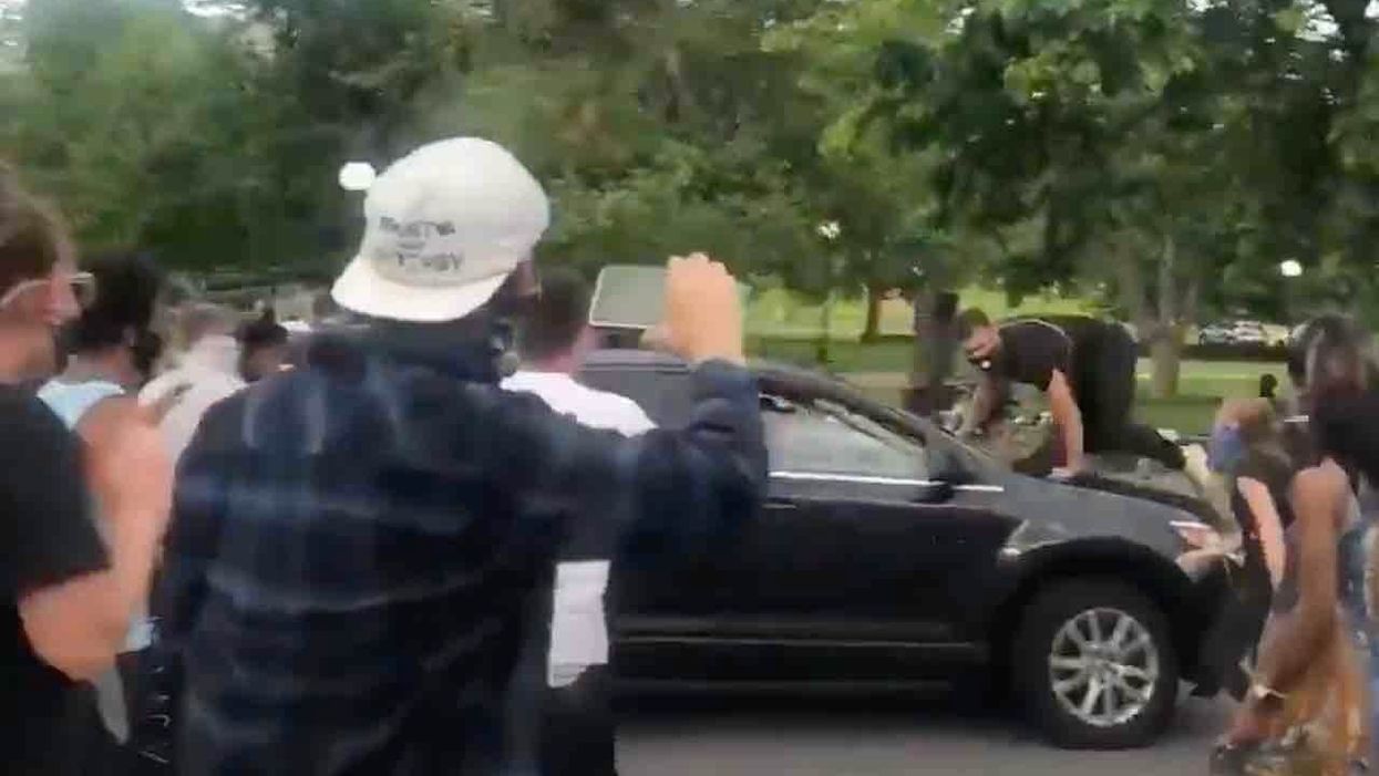 Protester jumps on hood of vehicle surrounded at intersection — but driver is in no mood to play