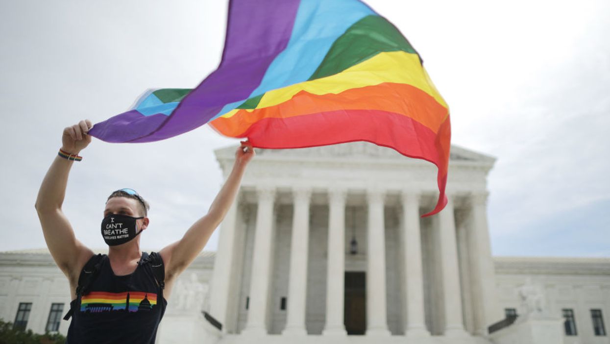 Protester with rainbow flag in front of Supreme Court