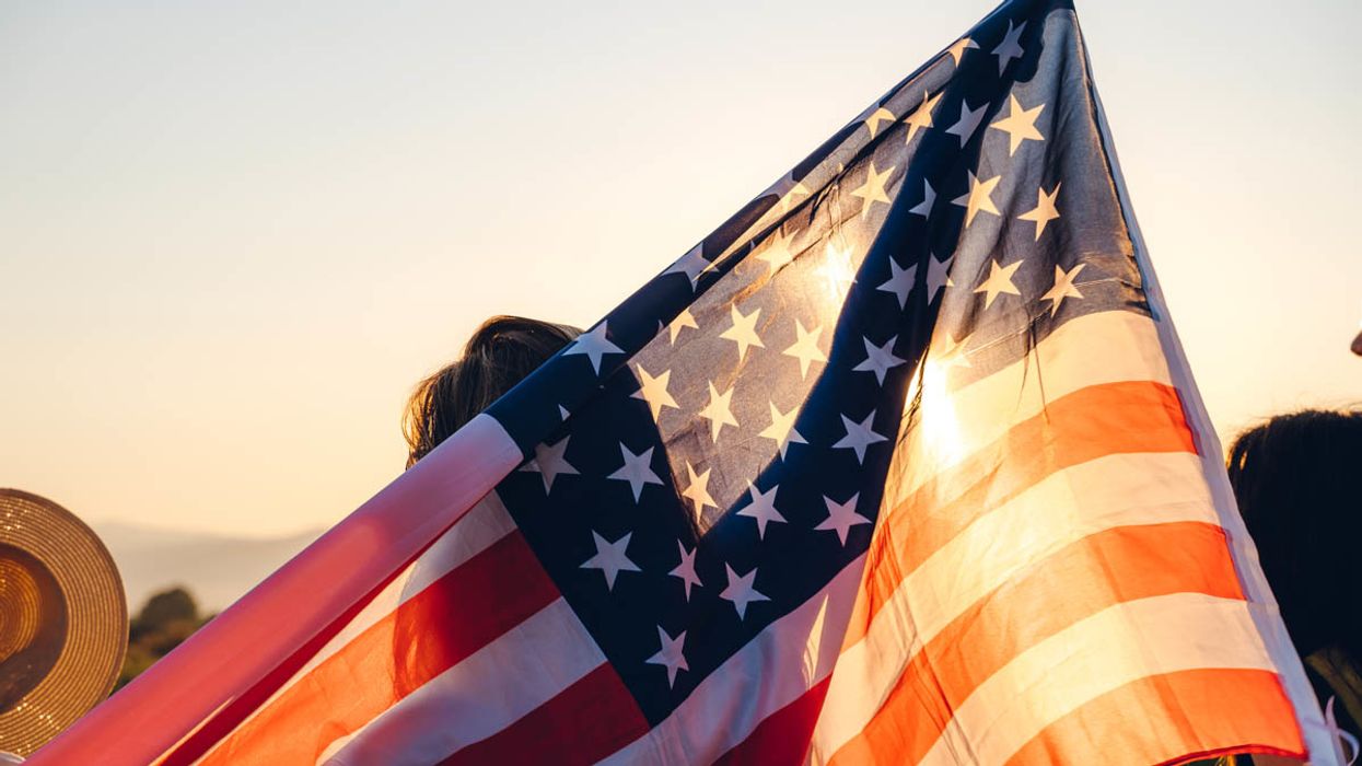Woman holding American flag in sunset